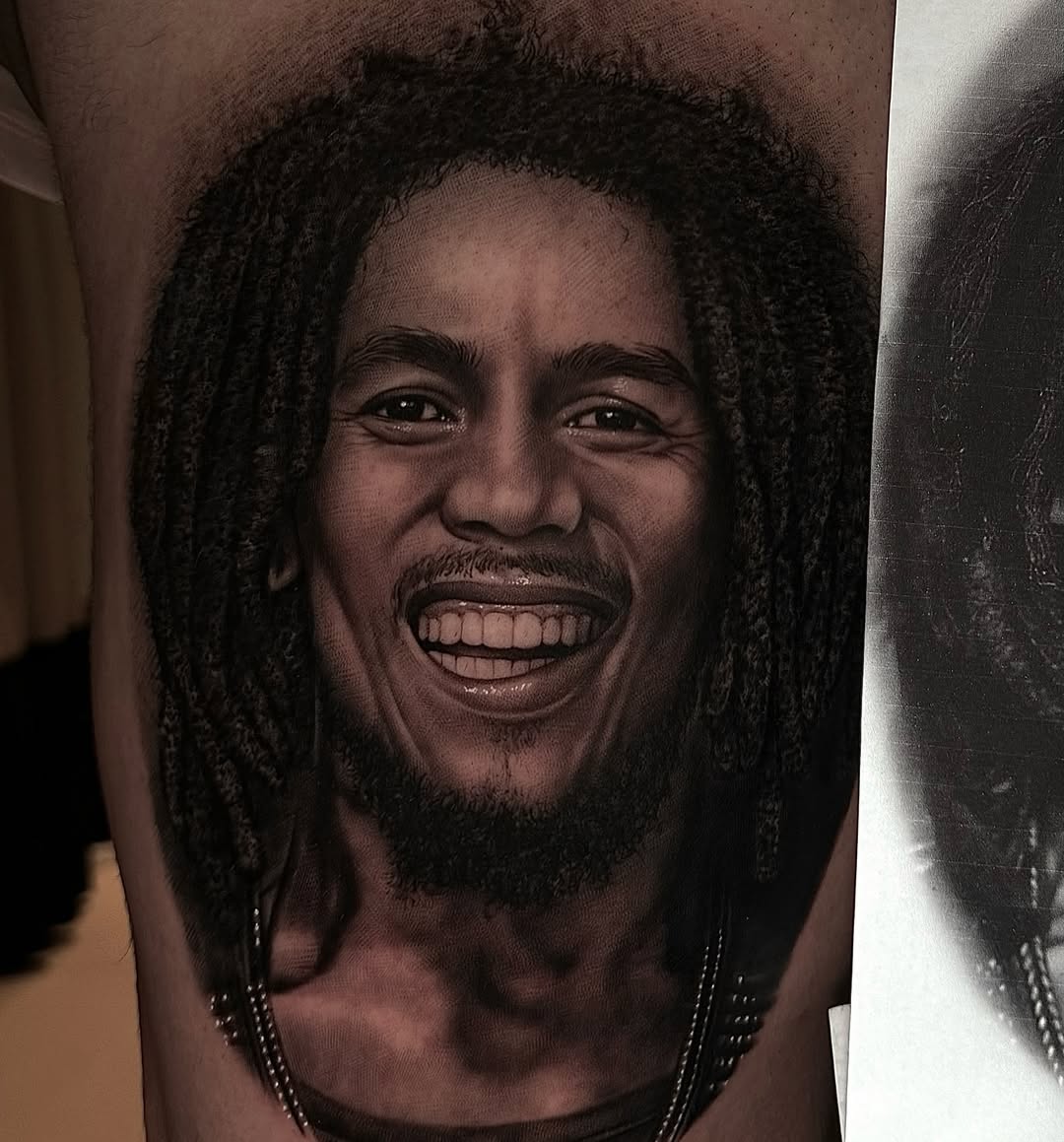 Portrait of Bob Marley tattooed in black and grey photorealism